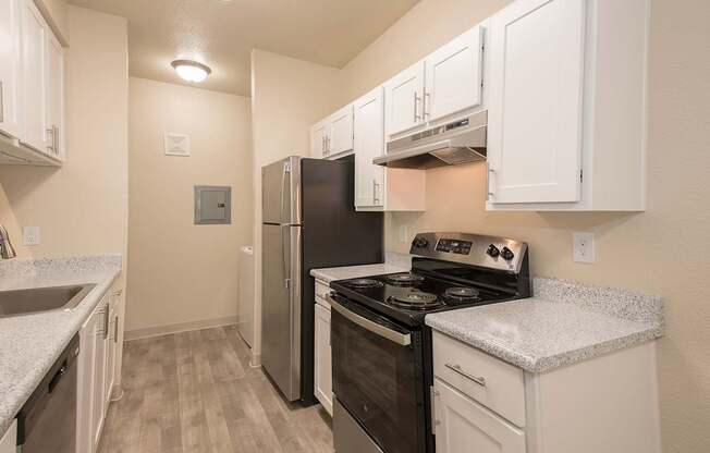 A kitchen with white cabinets and a black refrigerator at Sunset Summit, Rocklin, CA, 95765