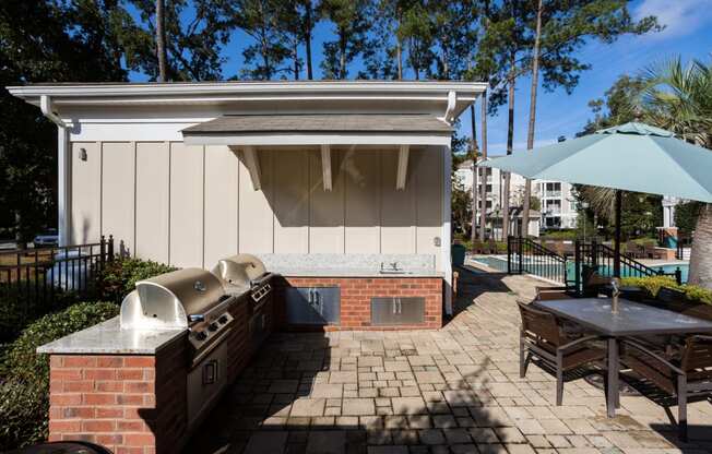a patio with a barbecue grill and a table with an umbrella