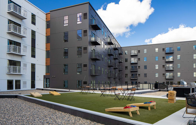 an exterior view of an apartment complex with tables and grass at Riverhouse Apartments, Fargo, ND