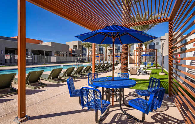 A blue umbrella is on a table with chairs around it.