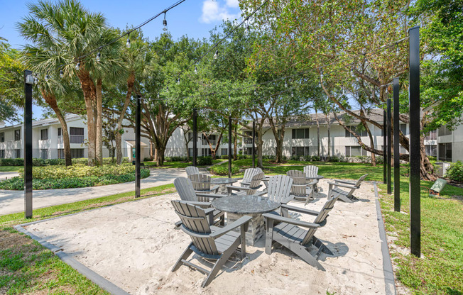 a sandy picnic area with tables and chairs in a park