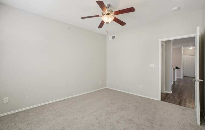A room with a ceiling fan and carpeted floor.