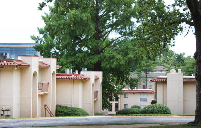 an apartment complex with trees in the foreground and a building in the background