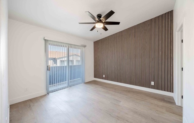 A room with a ceiling fan and sliding glass doors.
