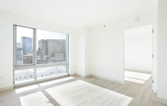 an empty room with a large window and a white rug