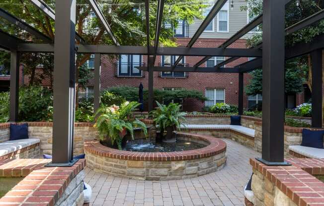 a courtyard with a fountain and a brick wall