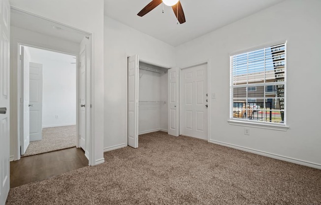 A room with a carpeted floor and a ceiling fan.