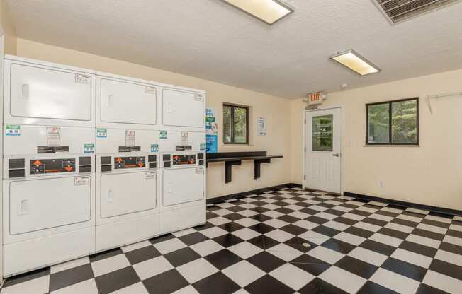 the laundry room has a checkered floor and white washers and dryers