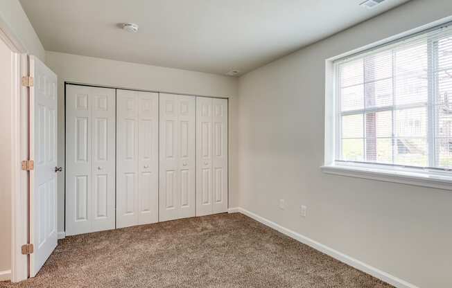 an empty bedroom with two closets and a window