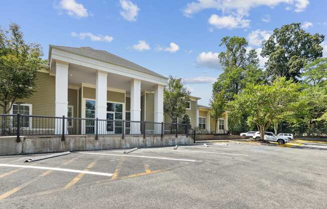 the entrance to a parking lot with a cream colored building with columns