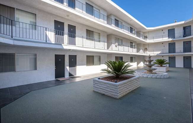 a courtyard with a fountain and a white building with black doors