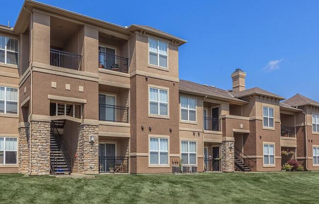 The exterior of apartment buildings overlooking a green lawn.