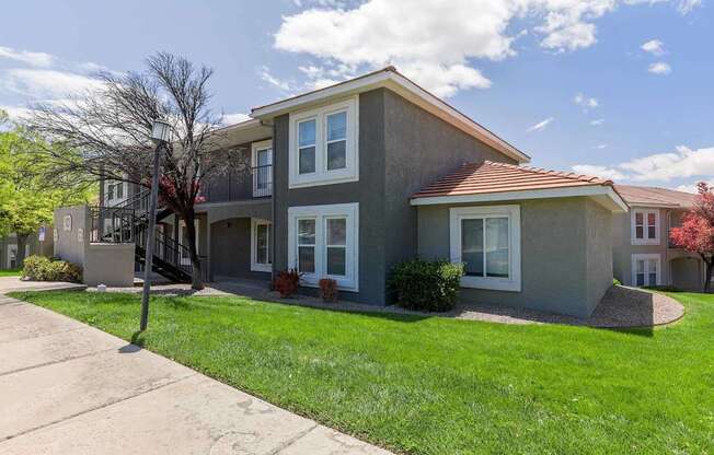 A grey house with a red roof and white windows.