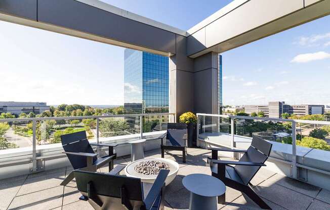 A patio with chairs and a table with a vase of flowers on it.