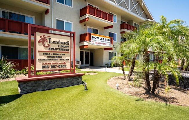A sign for Lombardi Luxury Apartments is displayed in front of a building.