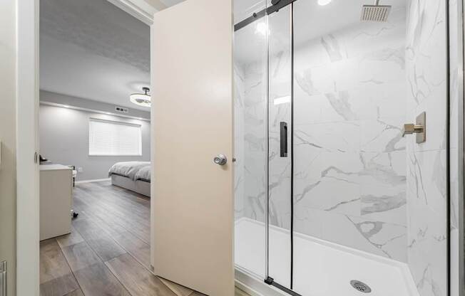 A bathroom with a marble wall and a walk-in shower.