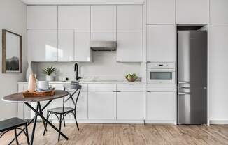 a white kitchen with a small table and a refrigerator  at Oslo, Seattle, 98102