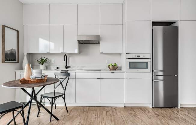a white kitchen with a small table and a refrigerator  at Oslo, Seattle, 98102