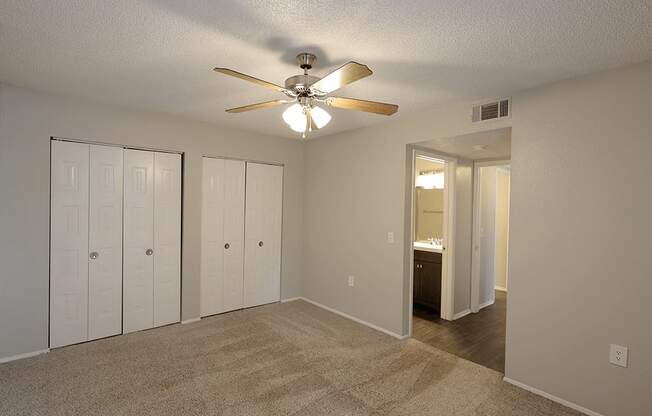 an empty living room with a ceiling fan and closet