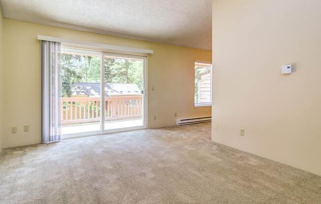 an empty living room with a sliding glass door and a balcony  at The Bluffs at Mountain Park, Oregon