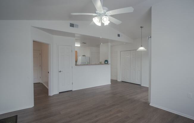 an empty living room with white walls and a ceiling fan