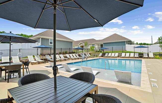 A poolside table with chairs and an umbrella over it. at Zora University, Charlotte, 28213