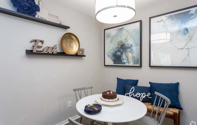 a dining area with a round table and chairs and pictures on the wall