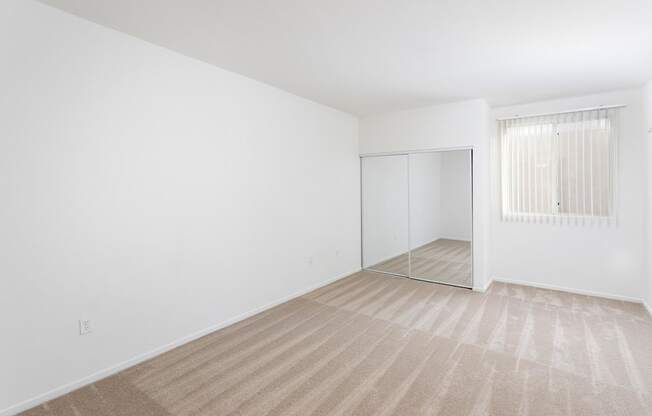 A room with a carpeted floor and a sliding door. at La Jolla Crossroads Apartments, San Diego, CA
