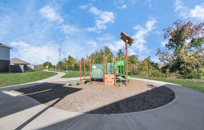 A playground with a green slide and a brown sandbox.