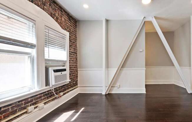 An apartment with a brick wall and a window with blinds at Brookmore Pasadena apartments.