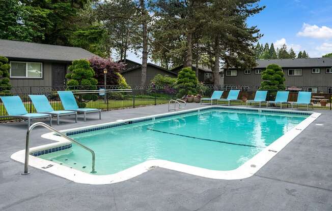 a swimming pool with blue chairs and a building in the background