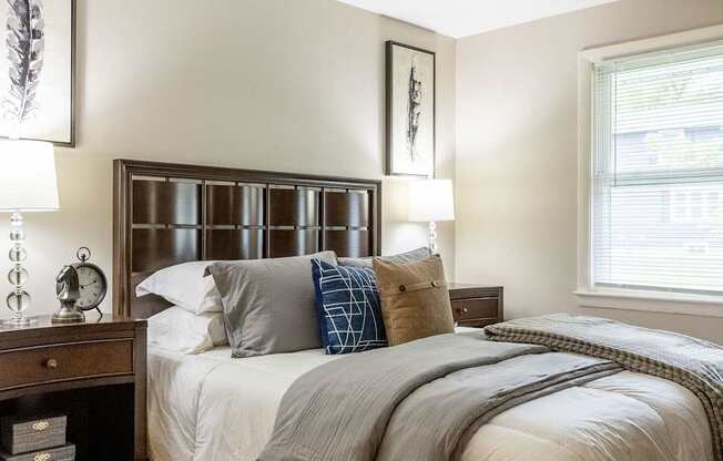 A bedroom with a bed, nightstand, and a window.