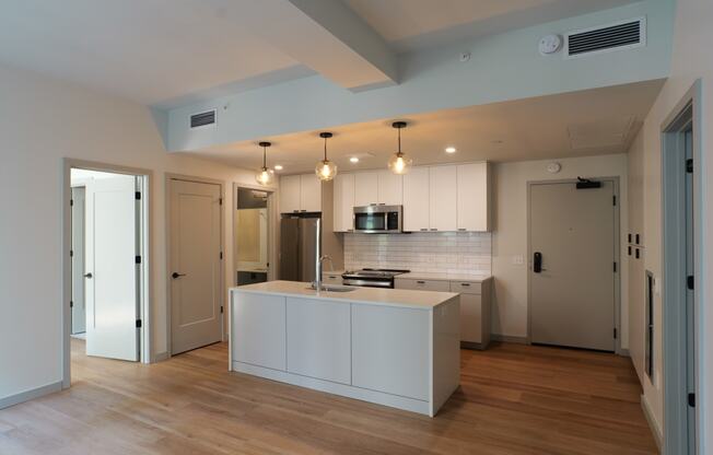 a kitchen with white cabinets and a white island in the middle at The Commonwealth Building, Pittsburgh, 15222