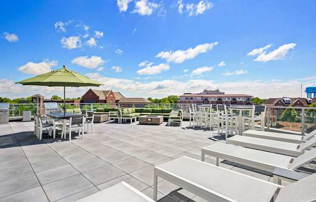 A patio with a table and chairs and a green umbrella.