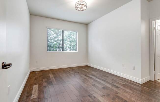 a bedroom with hardwood floors and white walls