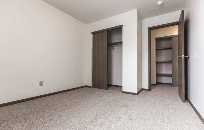 Grand Forks Primrose Apartments. An empty bedroom with a closet and an open door