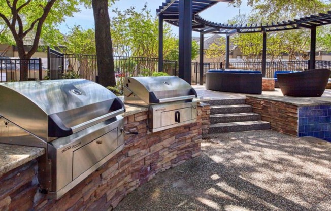 a patio with two bbq grills and a pergola