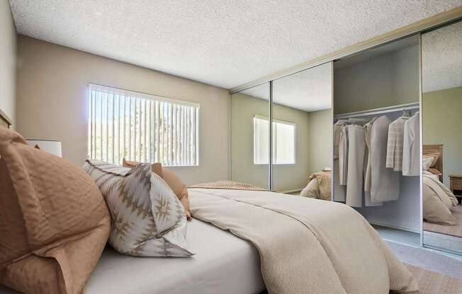 A bedroom with a bed, pillows, and a mirror.