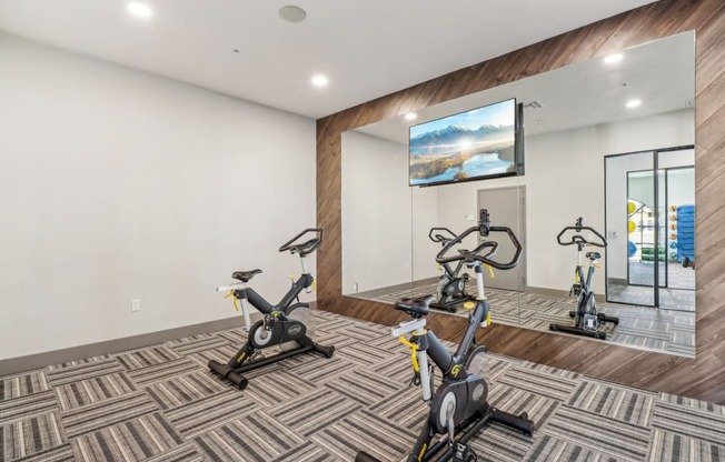 a gym with exercise bikes and a large mirror on the wall