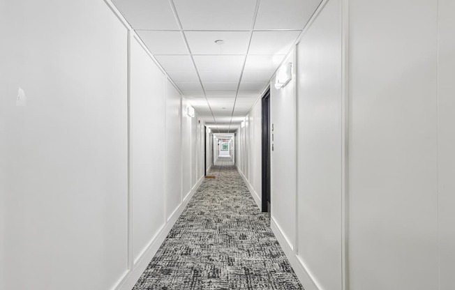 A long hallway with a carpeted floor and white walls.