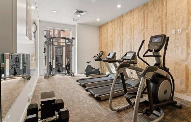 a gym with treadmills and other exercise equipment on a wooden wall at 200 City View, Provo