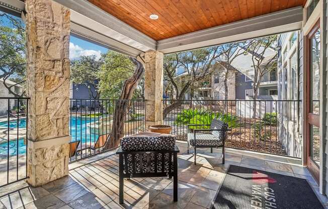 A patio with a black chair and a stone pillar.