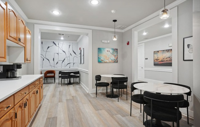 a dining room with a round table and chairs and a kitchen with a sink