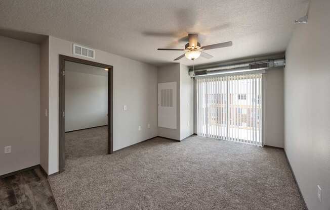 A room with a ceiling fan and sliding glass doors.