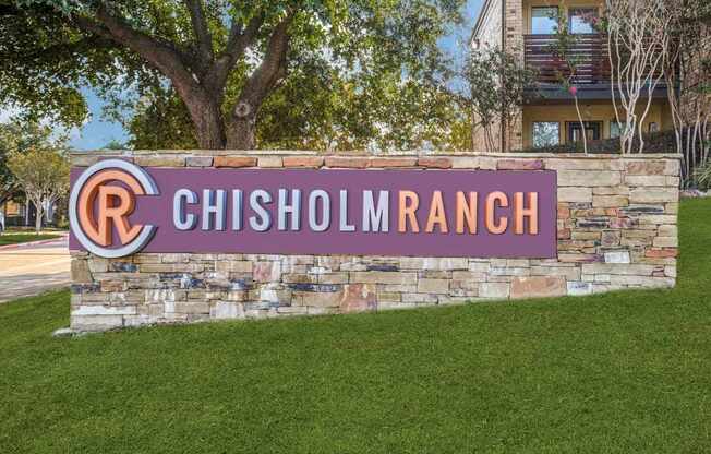 A sign that says Chisholm Ranch in front of a building.