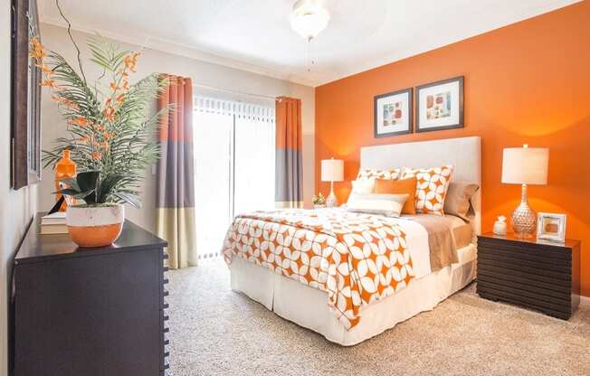 a bedroom with an orange accent wall and a bed