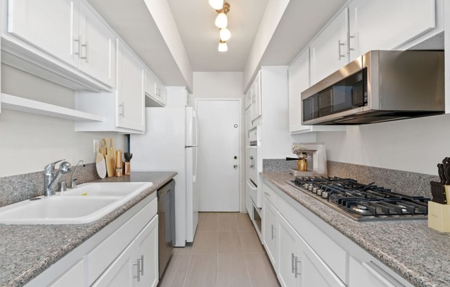 a kitchen with white cabinets and granite counter tops and a stove and microwave