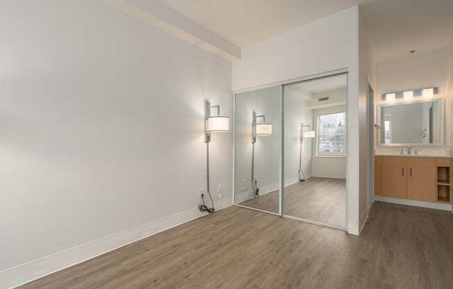 an empty living room with a mirror and a bathroom