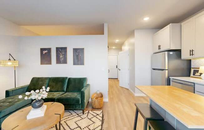 A living room with a green couch and a coffee table with a vase of flowers on it.