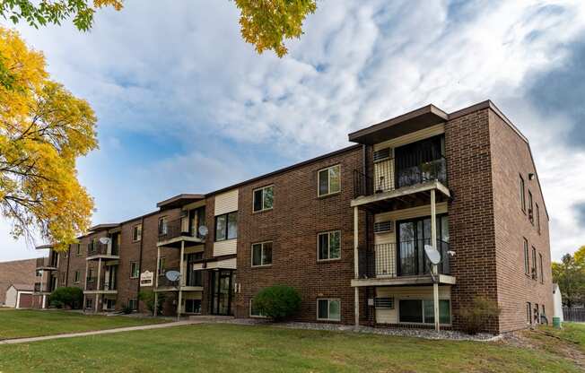 A brick apartment building with balconies on a cloudy day. Fargo, ND Long Island Apartments.